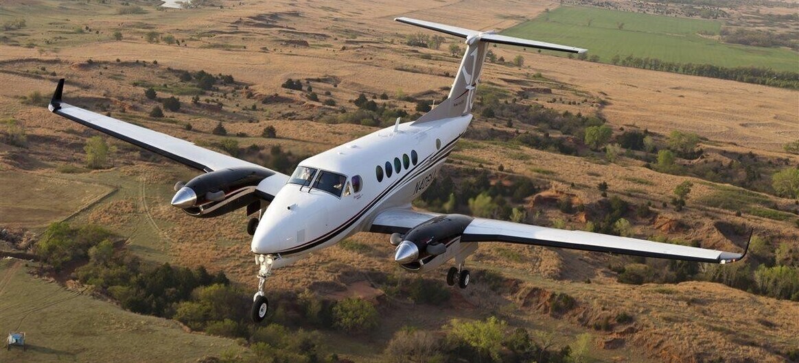 Beechcraft King Air 250 flying over field