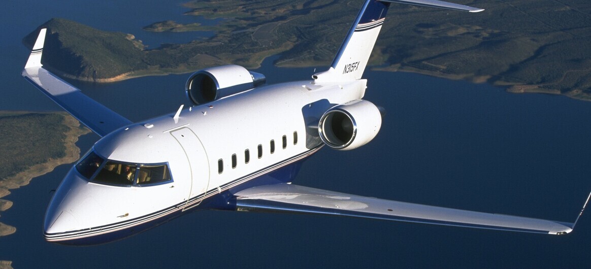 Bombardier Challenger 604 flying over land and sea