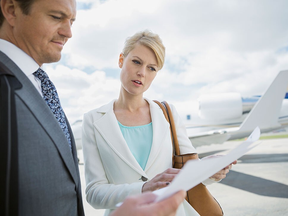 Business people examine paperwork in front of private jet